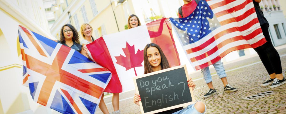 College students learning English with flags and blackboard, outdoors.